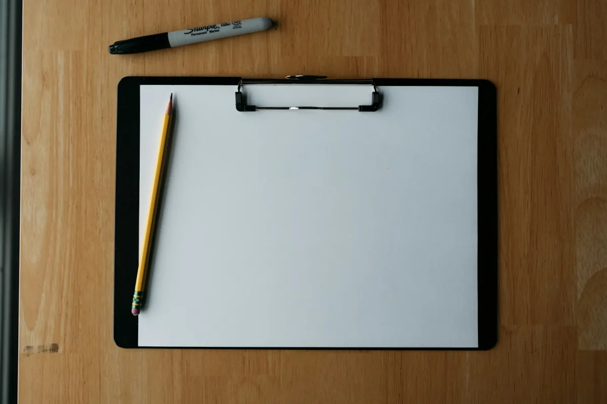 Leeres Klemmbrett mit Bleistift und Marker auf einem Holztisch, bereit für die Update-Checkliste
