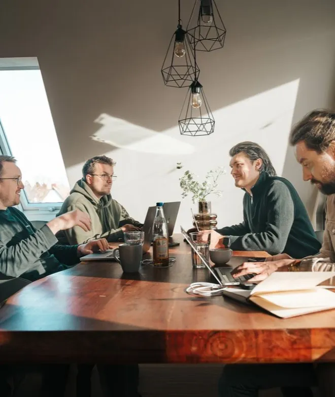 Besprechung an einem Tisch mit Laptops und Unterlagen, typische Arbeitssituation in einem betreuten Betrieb.
